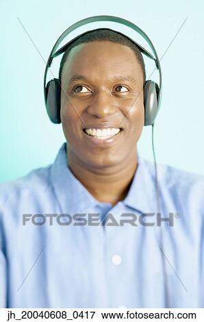 Mid adult man wearing headphones smiling View Large Photo Image Stock Photo - Mid adult man wearing headphones smiling. Fotosearch