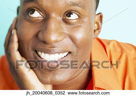 Stock Image - Mid adult man with his hand on his chin smiling. Fotosearch