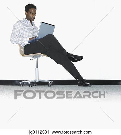 Stock Image - Mid adult man working on a laptop. Fotosearch
