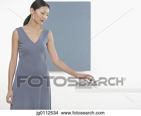Picture - Mid adult woman reaching for a mobile phone. Fotosearch