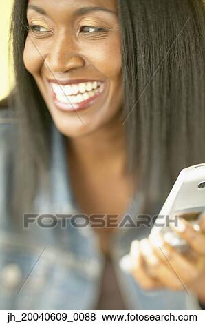 Mid adult woman smiling holding a mobile phone View Large Photo Image Stock Photo - Mid adult woman smiling holding a mobile phone. Fotosearch