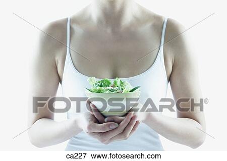 Mid section view of a young woman holding a bowl of salad View Large Photo Image Stock Photo - Mid section view of a young woman holding a bowl of salad. Fotosearch