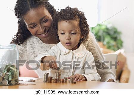 Stock Photography - Mother and her daughter counting coins. Fotosearch