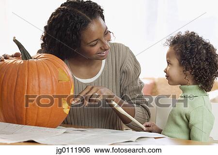 Stock Photograph - Mother carving pumpkin with her daughter. Fotosearch