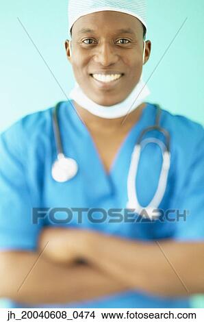 Portrait of a male doctor wearing full scrubs standing with his arms folded View Large Photo Image Picture - Portrait of a male doctor wearing full scrubs standing with his arms folded. Fotosearch