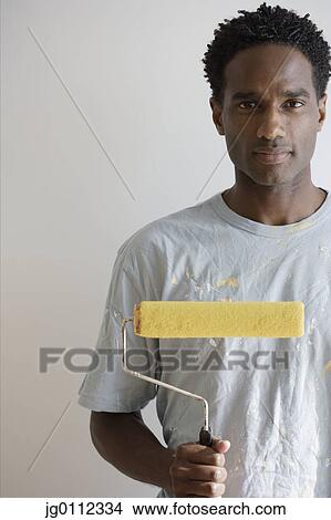 Portrait of a mid adult man holding a paint roller View Large Photo Image Picture - Portrait of a mid adult man holding a paint roller. Fotosearch