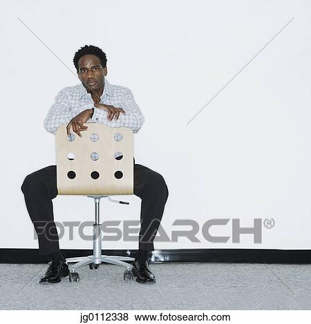 Portrait of a mid adult man sitting on a chair View Large Photo Image Stock Photo - Portrait of a mid adult man sitting on a chair. Fotosearch