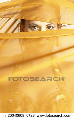 Stock Image - Portrait of a mid adult woman looking through silk cloth. Fotosearch