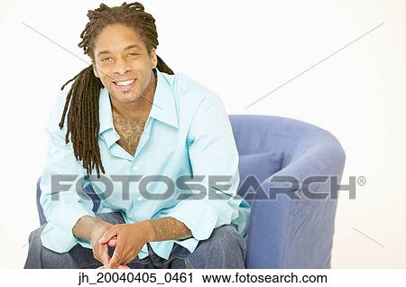 Portrait of a young man sitting on a couch smiling View Large Photo Image Stock Image - Portrait of a young man sitting on a couch smiling. Fotosearch