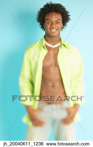 Portrait of a young man standing with his shirt unbuttoned View Large Photo Image Stock Photograph - Portrait of a young man standing with his shirt unbuttoned. Fotosearch