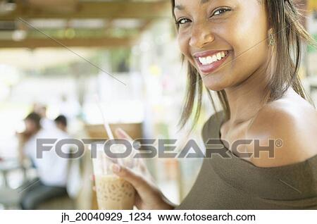 Portrait of a young woman holding a glass with a straw View Large Photo Image Picture - Portrait of a young woman holding a glass with a straw. Fotosearch
