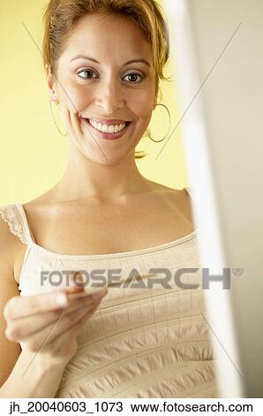 Portrait of a young woman holding a card smiling View Large Photo Image Stock Image - Portrait of a young woman holding a card smiling. Fotosearch