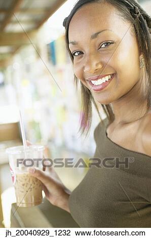 Portrait of a young woman holding a glass with a straw View Large Photo Image Stock Image - Portrait of a young woman holding a glass with a straw. Fotosearch