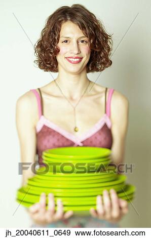 Portrait of a young woman holding stacks of plates View Large Photo Image Stock Photo - Portrait of a young woman holding stacks of plates. Fotosearch