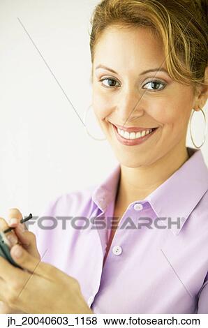 Stock Photo - Portrait of a young woman operating a hand held device. Fotosearch
