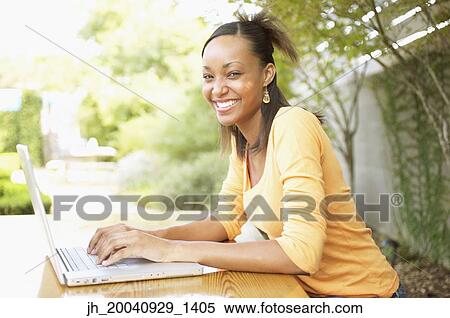 Portrait of a young woman working on a laptop smiling View Large Photo Image Stock Photography - Portrait of a young woman working on a laptop smiling. Fotosearch