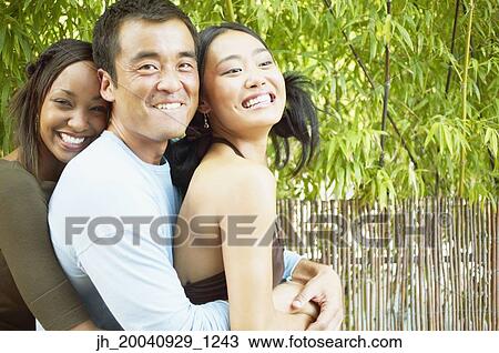 Portrait of two young women and a mid adult man holding each other View Large Photo Image Stock Image - Portrait of two young women and a mid adult man holding each other. Fotosearch