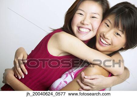 Portrait of two young women holding each other smiling View Large Photo Image Stock Photo - Portrait of two young women holding each other smiling. Fotosearch