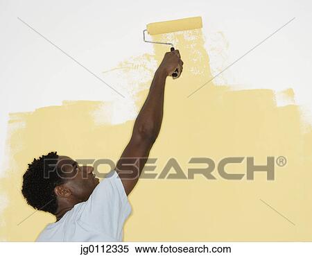 Rear view of a mid adult man painting a wall with a paint roller View Large Photo Image Stock Photography - Rear view of a mid adult man painting a wall with a paint roller. Fotosearch
