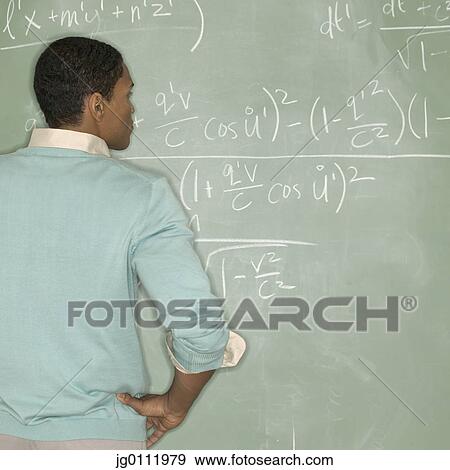 Rear view of a teacher looking at a blackboard View Large Photo Image Stock Photo - Rear view of a teacher looking at a blackboard. Fotosearch