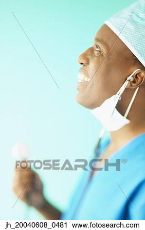Side profile of a male doctor holding a stethoscope smiling View Large Photo Image Stock Image - Side profile of a male doctor holding a stethoscope smiling. Fotosearch