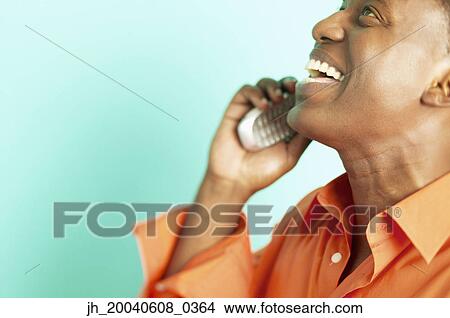 Side profile of a mid adult man talking on a mobile phone View Large Photo Image Picture - Side profile of a mid adult man talking on a mobile phone. Fotosearch