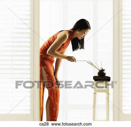 Stock Photo - Side profile of a young woman burning incense. Fotosearch