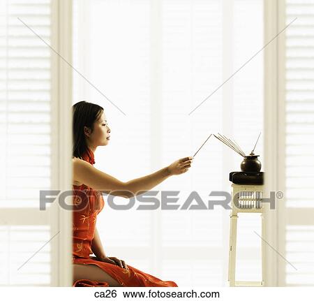 Stock Photograph - Side profile of a young woman burning incense. Fotosearch
