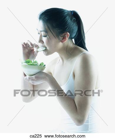 Side profile of a young woman eating salad View Large Photo Image Stock Photography - Side profile of a young woman eating salad. Fotosearch