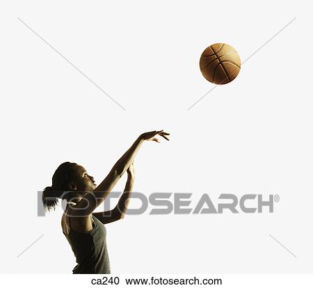 Stock Image - Side profile of a young woman playing basketball. Fotosearch