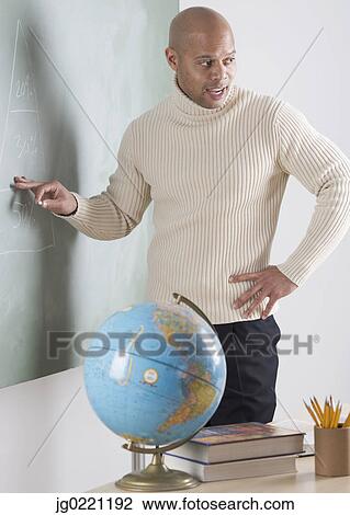 Teacher standing in a classroom in front of a blackboard View Large Photo Image Stock Image - Teacher standing in a classroom in front of a blackboard. Fotosearch