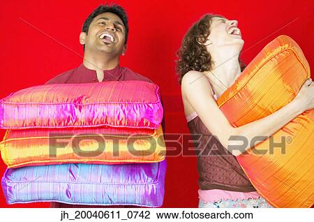 Young couple holding cushions laughing View Large Photo Image Stock Image - Young couple holding cushions laughing. Fotosearch