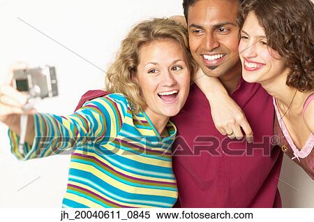 Young man and two young women taking a photograph of themselves View Large Photo Image Stock Photography - Young man and two young women taking a photograph of themselves. Fotosearch