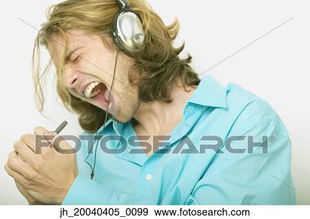 Young man singing into a pen wearing headphones View Large Photo Image Stock Photo - Young man singing into a pen wearing headphones. Fotosearch