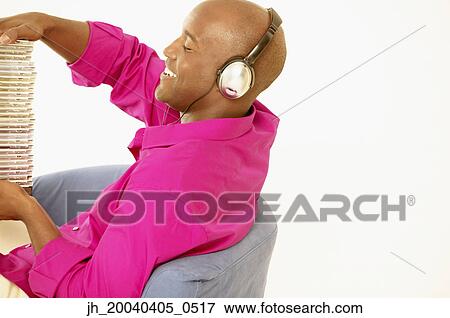 Young man sitting on a couch holding a stack of cds View Large Photo Image Stock Photo - Young man sitting on a couch holding a stack of cds. Fotosearch