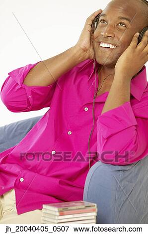 Young man sitting wearing headphones View Large Photo Image Stock Photo - Young man sitting wearing headphones. Fotosearch