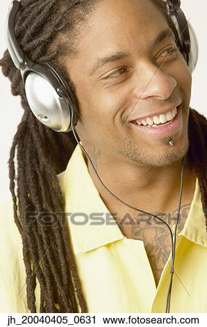 Young man wearing headphones smiling View Large Photo Image Stock Image - Young man wearing headphones smiling. Fotosearch