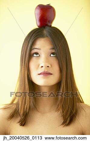 Young woman balancing an apple on her head View Large Photo Image Stock Image - Young woman balancing an apple on her head. Fotosearch