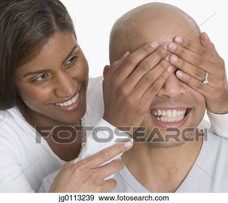 Young woman covering the eyes of a young man View Large Photo Image Stock Photo - Young woman covering the eyes of a young man. Fotosearch