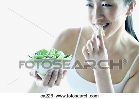 Stock Photo - Young woman eating salad. Fotosearch