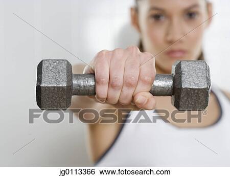 Stock Photograph - Young woman holding a dumbbell. Fotosearch
