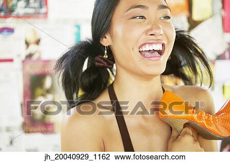 Young woman holding high heel shoes laughing View Large Photo Image Stock Image - Young woman holding high heel shoes laughing. Fotosearch