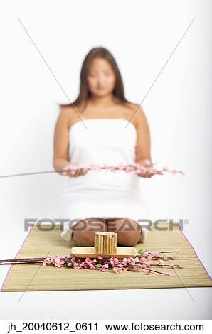 Young woman kneeling on a straw mat holding plants View Large Photo Image Stock Image - Young woman kneeling on a straw mat holding plants. Fotosearch