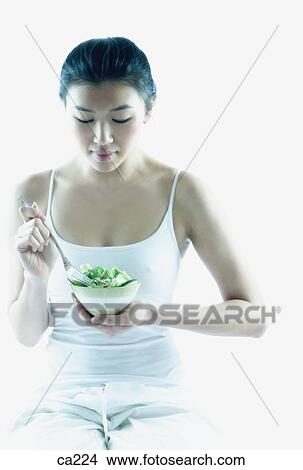 Picture - Young woman sitting holding a bowl. Fotosearch