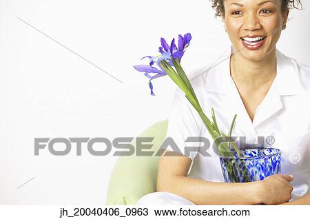 Young woman sitting on a couch holding a flower vase View Large Photo Image Stock Image - Young woman sitting on a couch holding a flower vase. Fotosearch