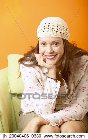 Young woman sitting on a couch smiling View Large Photo Image Stock Image - Young woman sitting on a couch smiling. Fotosearch