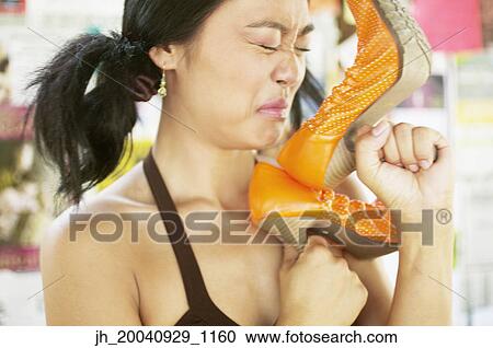 Stock Image - Young woman smelling high heel shoes. Fotosearch