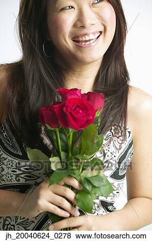Young woman smiling holding roses View Large Photo Image Stock Photo - Young woman smiling holding roses. Fotosearch