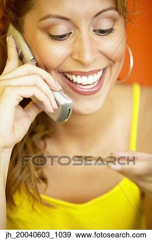 Young woman smiling talking on a mobile phone View Large Photo Image Stock Photo - Young woman smiling talking on a mobile phone. Fotosearch