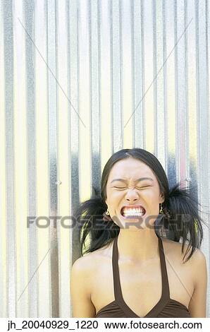 Young woman standing against a corrugated metal wall making a face View Large Photo Image Stock Image - Young woman standing against a corrugated metal wall making a face. Fotosearch